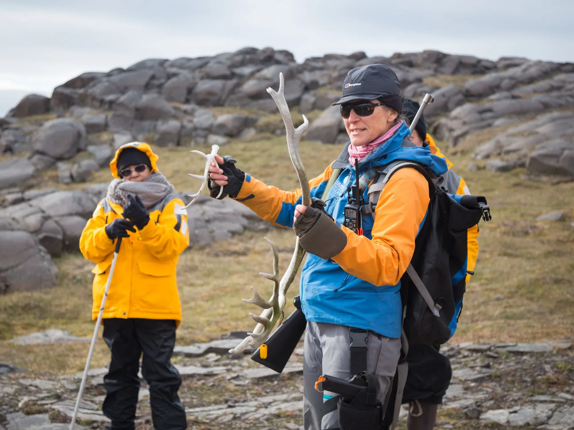 An expedition guide holding up reindeer antlers to a guest on the tundra