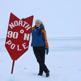 Liz Teague standing at the 90 degrees North sign at the North Pole