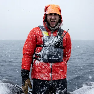 Will Abbott laughing in falling snow on a zodiac in Antarctica