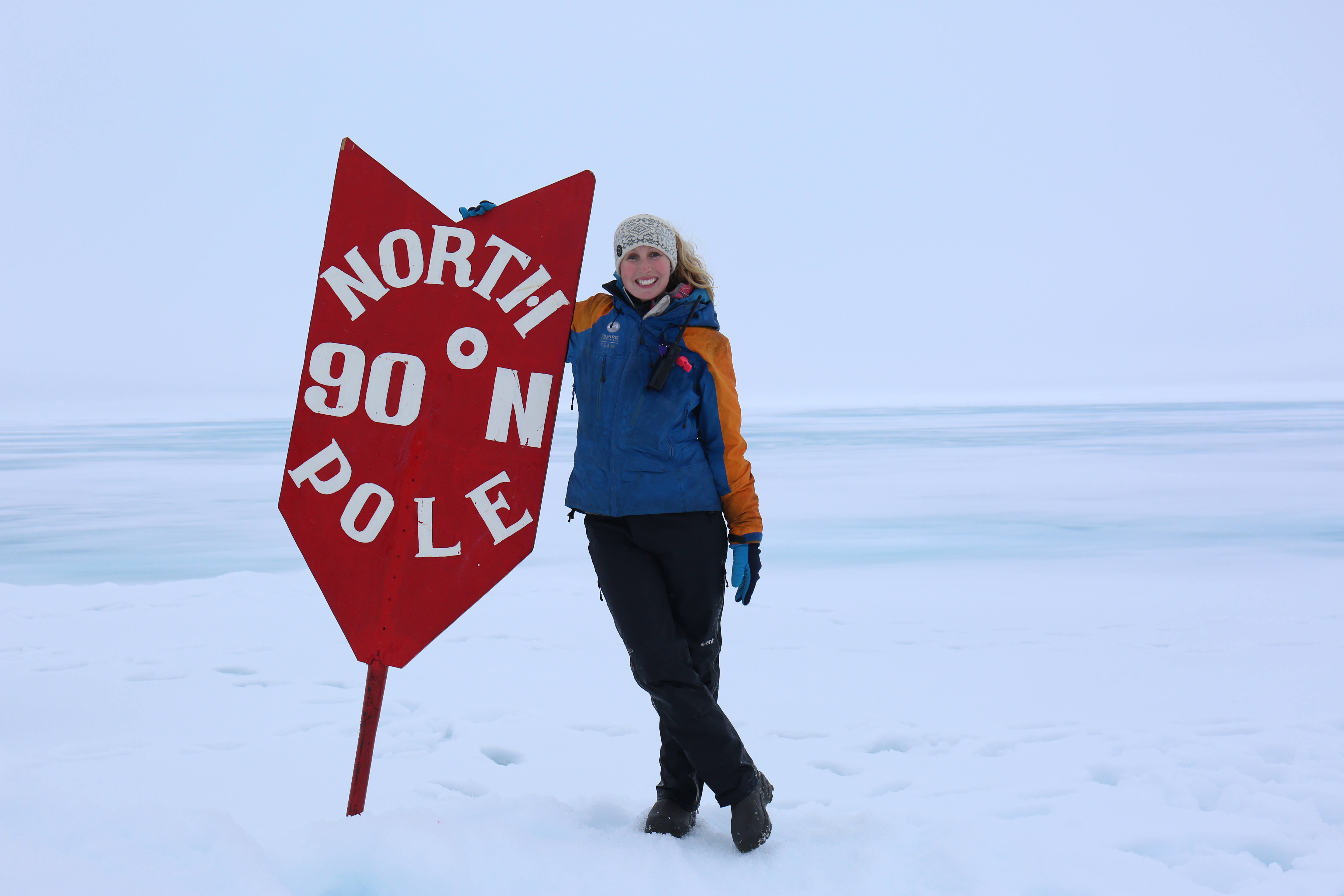 Liz Teague standing at the 90 degrees North sign at the North Pole