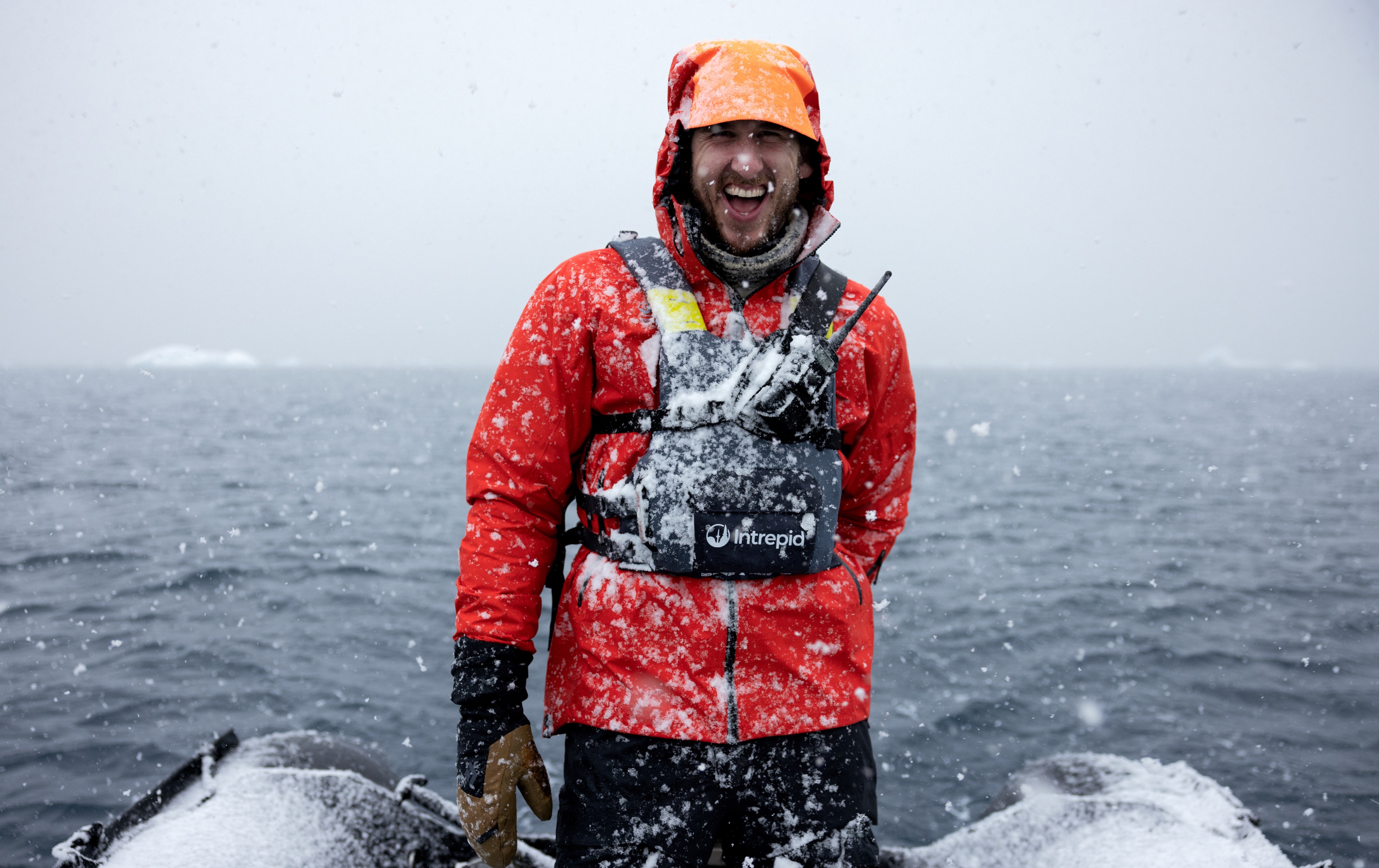 Will Abbott laughing in falling snow on a zodiac in Antarctica